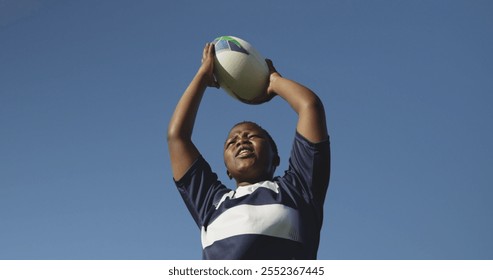 Front view low angle of a young adult biracial female rugby player shouting and throwing the ball to teammates during a rugby match - Powered by Shutterstock