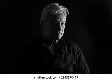 Front View Of Low Key Portrait Of A Senior Man Serious And  Looking At Camera On Black Background