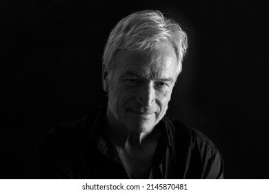 front view of low key portrait of a senior man looking at camera on black background