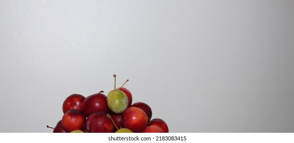 Front view of luscious red plums and green plums on a glass serving platter on a white table and in front of a white background - Shutterstock ID 2183083415