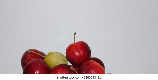 Front view of luscious red plums and green plums on a glass serving platter on a white table and in front of a white background - Shutterstock ID 2183083421