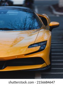 A front view of a luxurious yellow supercar parked outside