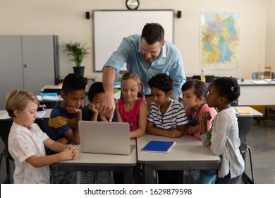 Front View Of A Male Teacher Teaching Kids On Laptop In Classroom Of Elementary School