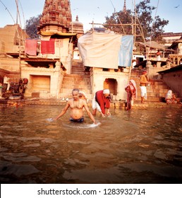 Front view of a man bathing in a river beside a temple.