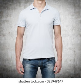 Front View Of A Man In A Light Blue Polo Shirt And Denims. Concrete Background.