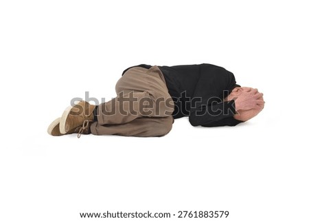 front view of  man lying on the ground in the fetal position, covering his face