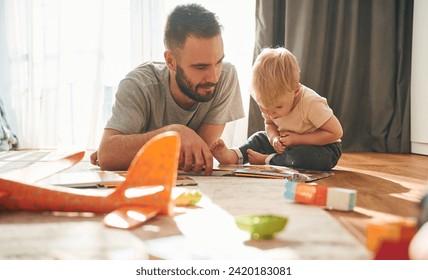 Front view. Man is playing with his little son in the domestic room. - Powered by Shutterstock