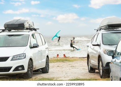 Front view many cars parked with surf board kite equipment on sand beach, van vehicle with rooftop box ocean sea beach watersport spot camp. Adventure travel water sport acitivity