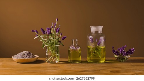 Front view of many lavender-based items, placed side by side and displayed on the table. Some lavender is in a glass vase, some is soaked in essential oil, and dried buds are placed on a plate.
