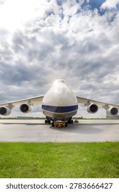 Front view massive cargo freight aircraft parked airport apron under dramatic cloudy sky. Aviation scene widebody jet powerful engines, wide wings and industrial airfreight transportation