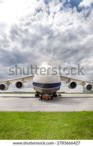 Front view massive cargo freight aircraft parked airport apron under dramatic cloudy sky. Aviation scene widebody jet powerful engines, wide wings and industrial airfreight transportation