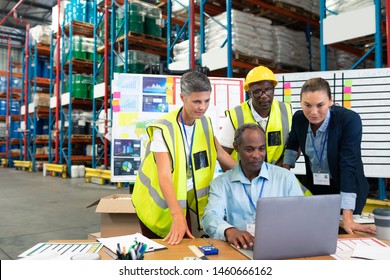 Front view of mature African-american male supervisor with his diverse coworkers discussing over laptop at desk in warehouse. This is a freight transportation and distribution warehouse. Industrial - Powered by Shutterstock