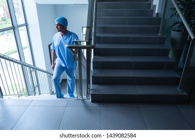 Front view of mature Caucasian male surgeon looking through window while climbing up the stairs of hospital - Powered by Shutterstock