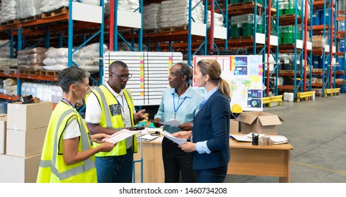 Front View Of Mature Diverse Staffs Discussing Over Document In Warehouse. This Is A Freight Transportation And Distribution Warehouse. Industrial And Industrial Workers Concept