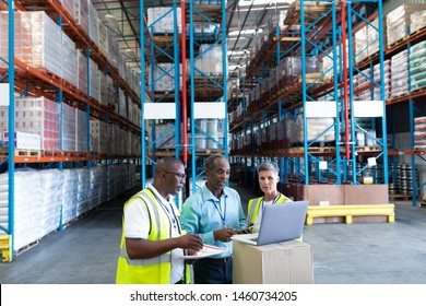 Front View Of Mature Diverse Warehouse Staffs Discussing Over Laptop In Warehouse. This Is A Freight Transportation And Distribution Warehouse. Industrial And Industrial Workers Concept