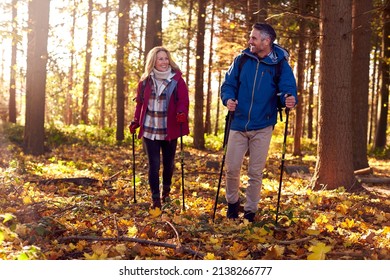 Front View Of Mature Retired Couple Walking Through Fall Or Winter Countryside Using Hiking Poles