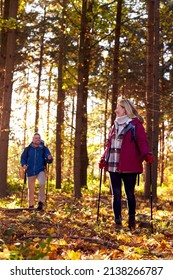 Front View Of Mature Retired Couple Walking Through Fall Or Winter Countryside Using Hiking Poles