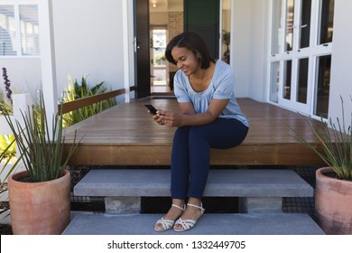 Front View Of Mature Woman Using Mobile Phone On The Porch At Home