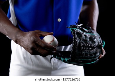 Front view mid section of an African American male baseball player, a pitcher, wearing a team uniform and a mitt, holding a baseball - Powered by Shutterstock