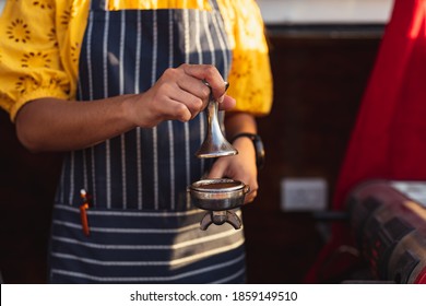 Front View Mid Section Of A Young Mixed Race Woman Wearing An Apron Preparing Coffee In A Food Vending Truck