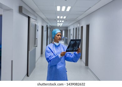 Front view of Mixed race female surgeon examining x-ray in the corridor of hospital. Healthcare workers in the Coronavirus Covid19 pandemic
