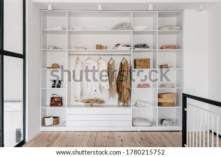 Front view of modern and large wardrobe in dressing room with fashionable woman clothes wear, shoes and bag
