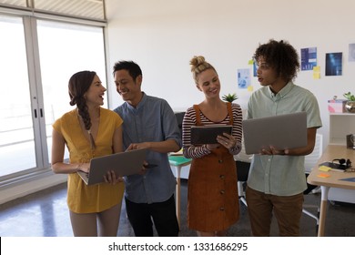 Front view of multi-ethnic business colleagues discussing plans over laptop and digital tablet in modern office - Shutterstock ID 1331686295