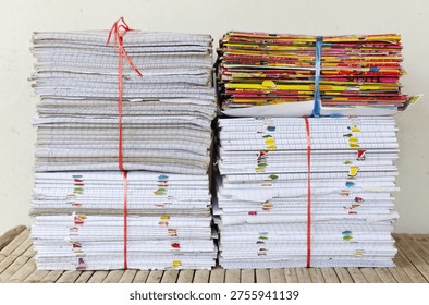 A front view of multiple stacks of old school notebooks and colorful books, securely tied with red and blue plastic ropes, ready for recycling or storage.