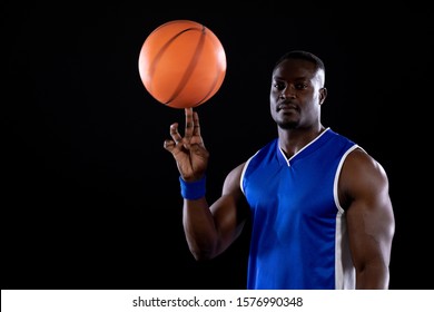 Front view of a muscular African American male basketball player wearing team colours spinning a basketball on his finger tip and looking to camera - Powered by Shutterstock