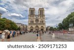 Front view of Notre-Dame de Paris timelapse hyperlapse. Medieval Catholic cathedral on the Cite Island in Paris, France. Long queue of tourists at the entrance. Cloudy sky at summer day