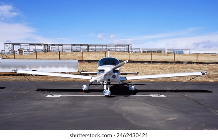 A Front View od a Small Single Engine Passenger Plane Tied Down at an Airport Ramp