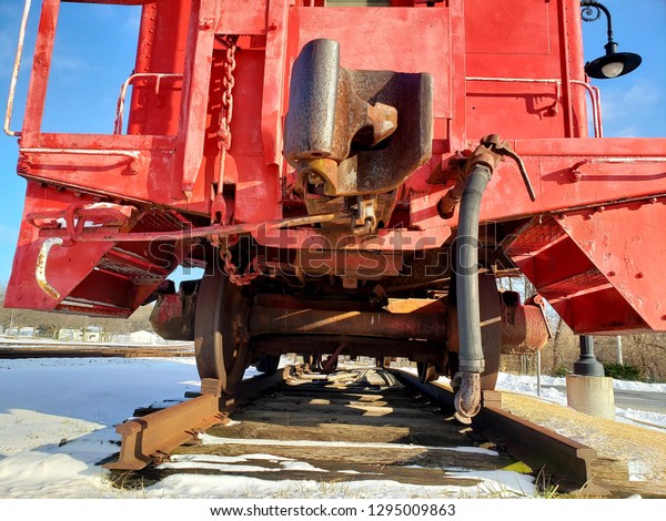 front view of an old red train\
coupler and cable assembly from the ground with old style lamp post\
in background stealing attention in Independence Missouri\
