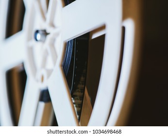 Front view of an old-fashioned antique Super 8mm film projector, projecting a beam of light in a dark room next to a stack of unraveled film reels. - Powered by Shutterstock