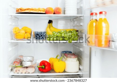 Front View of open two door fridge or refrigerator door filled with fresh fruits, vegetables, juice, full of healthy food items and ingredients inside. Electric Kitchen and Domestic Major Appliances