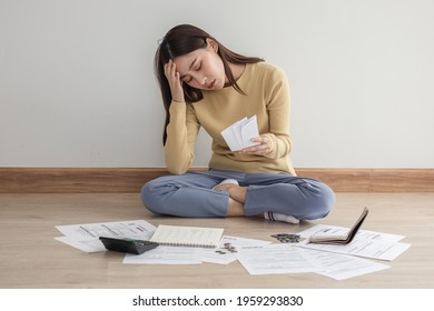 Front view owe asian woman, female sitting on floor home, stressed and confused by calculate expense from invoice or bill, have no money to pay, mortgage or loan. Debt, bankruptcy or bankrupt concept. - Shutterstock ID 1959293830