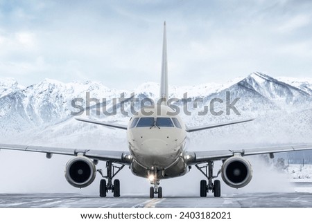 Front view of the passenger aircraft taxiing on taxiway on the background of high snow capped mountains