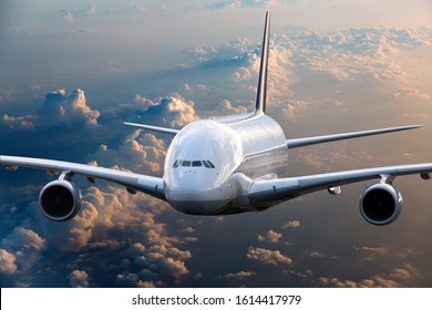 Front view of the passenger double decker plane in flight. Aircraft fies high over the clouds during sunset.