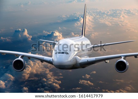 Front view of the passenger double decker plane in flight. Aircraft fies high over the clouds during sunset.