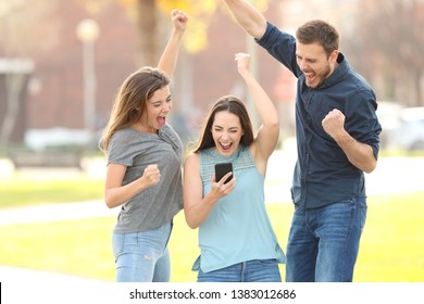 Front view portrait of 3 excited friends jumping reading good netw on phone