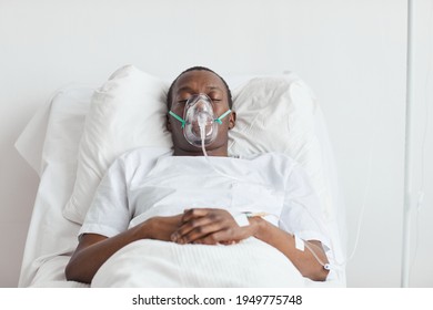 Front view portrait of African-American man on hospital bed with oxygen mask in white room, copy space - Powered by Shutterstock
