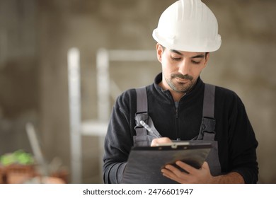 Front view portrait of a construction worker taking notes on clipboard in a house - Powered by Shutterstock