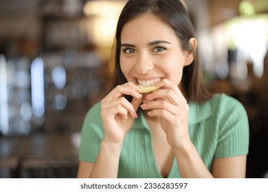 Front view portrait of a happy woman in a bar biting lemon - Powered by Shutterstock
