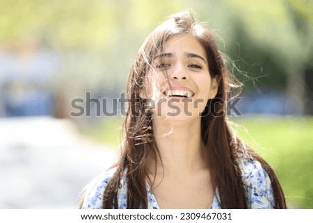 Front view portrait of a happy woman laughing with tousled hair a windy day