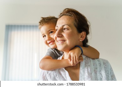 Front view portrait of mature caucasian woman and little boy child hugging her from back - Mother and son in at home bonding having fun - real people domestic life happy joy and bonding concept - Shutterstock ID 1788533981