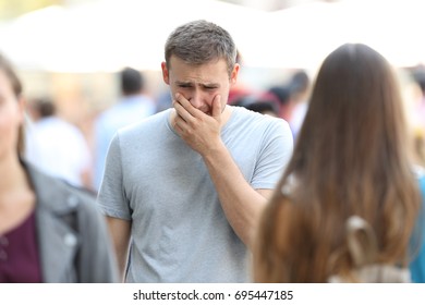 Front view portrait of a sad boy walking on the street being ignored by the crowd
