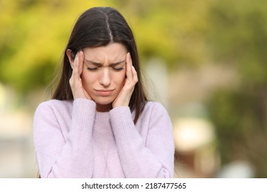 Front view portrait of a teen stressed suffering migraine in a park - Powered by Shutterstock