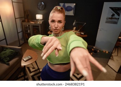 Front view portrait of trendy blonde woman recording dance video indoors and looking at camera copy space - Powered by Shutterstock