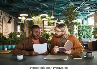 Front View Portrait Of Two Contemporary Men Collaborating On Project During Business Meeting In Green Office Or Cafe Interior, Copy Space