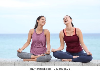 Front view portrait of two happy women doing yoga laughing on the beach - Powered by Shutterstock