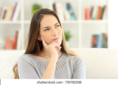 Front view portrait of a woman wondering sitting on a sofa at home - Powered by Shutterstock